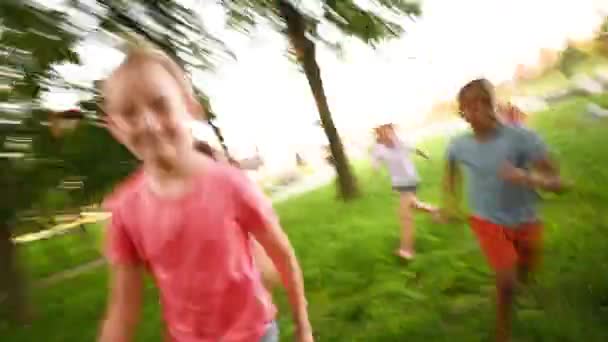 Группа дошкольников, бегающих по траве на фоне парка и зелени. — стоковое видео
