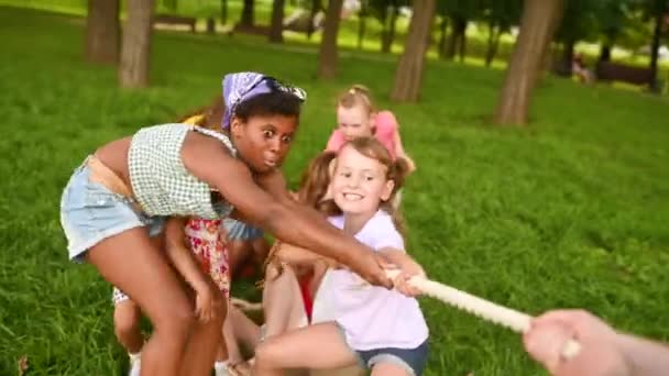 Een groep kinderen concurreren in een sleepboot in de open lucht tegen de achtergrond van gras en park. — Stockvideo