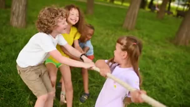 Un groupe d'enfants concourent dans un remorqueur de guerre en plein air sur fond d'herbe et de parc. — Video