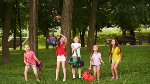 Grupp av skolbarn glädjas i början av sommarlovet, kasta upp sina skolryggsäckar och skratta. — Stockvideo