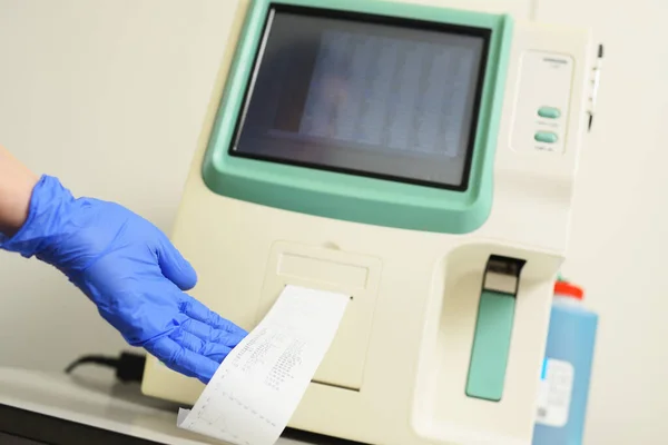 Un asistente de laboratorio examina una muestra de sangre en un analizador en una clínica microbiológica moderna. — Foto de Stock