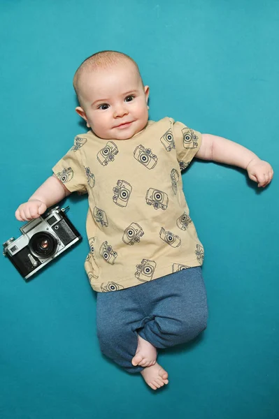 Criança pequena ou menino com uma câmera vintage sorri em um fundo azul — Fotografia de Stock