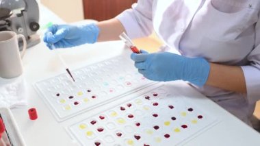 Laboratuvar çalışanı kan grubu ve Rh faktörü tanımlaması için cuvette tutuyor.