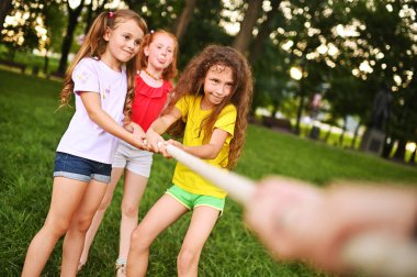 Bir grup anaokulu çocuğu bir parkın ve yeşilliğin arka planına karşı bir çekişme mücadelesinde yarışacak..