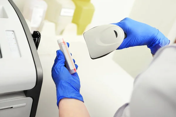 Técnico médico con guantes de goma azul escanea el código del tubo de ensayo en un laboratorio bioquímico moderno. — Foto de Stock