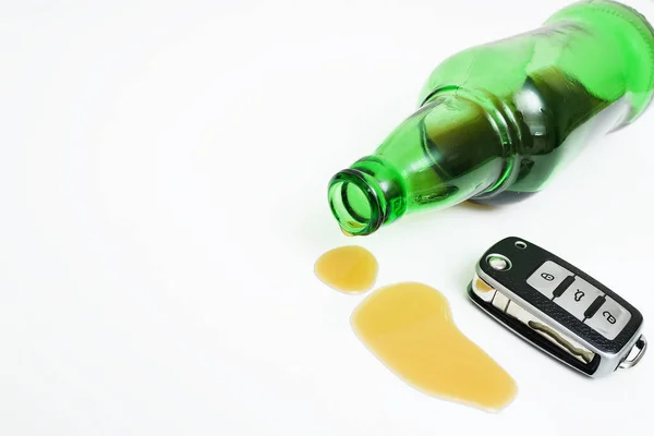 Зелена скляна пляшка з залишком алкоголю або пива і електронний ключ автомобіля на білому тлі . — стокове фото