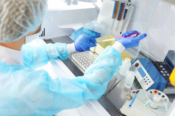 Oficial médico del laboratorio de PCR lleva a cabo un estudio con un dispensador en sus manos. — Foto de Stock