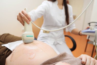 Doktor modern bir klinikte hamile bir kadının ceninini ultrason ile muayene ediyor..