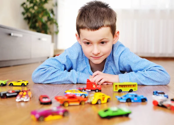 Klein kind kleuter spelen speelgoed auto 's op de houten vloer in een lichte kamer — Stockfoto