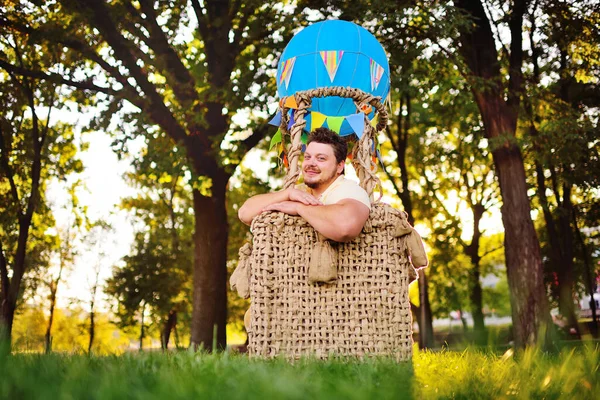 A large adult bearded man in the basket of a toy balloon. — Stock Photo, Image