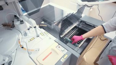 Modern bir mikrobiyoloji laboratuvarının kadın çalışanı kan örneklerini bir biyokimya laboratuvarına kan analizcisi olarak gönderir..