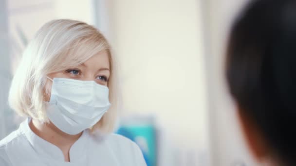 Personnel médical femme dans un masque stérile parler à un patient et sourire. — Video