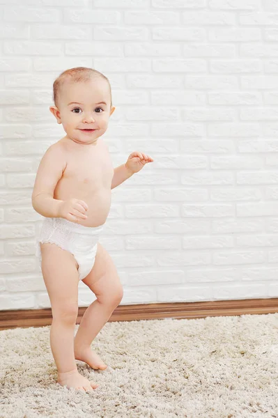 Cute baby boy in a diaper makes the first steps u smiles — Stock Photo, Image