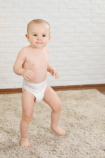 Cute baby boy in a diaper makes the first steps u smiles — стоковое фото