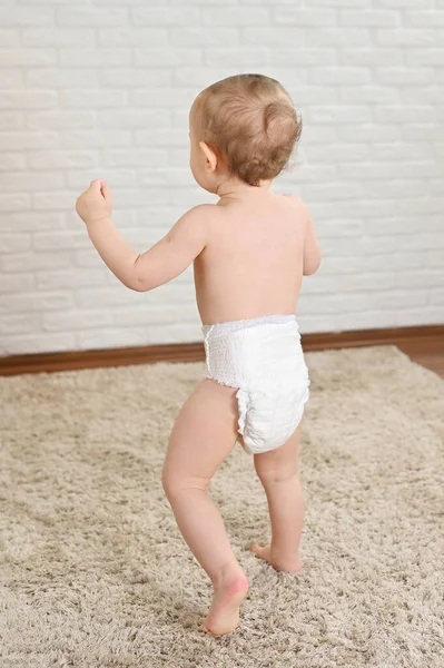 Petit enfant dans une couche jetable contre un mur blanc - vue de dos — Photo