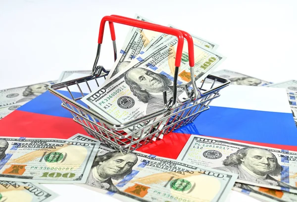 Kosár egy szupermarket amerikai dollárral a háttérben az orosz trikolor zászló. — Stock Fotó