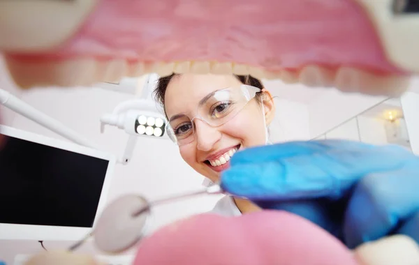Ładna młoda dentystka bada zęby pacjentów. Widok z wnętrza szczęki. — Zdjęcie stockowe