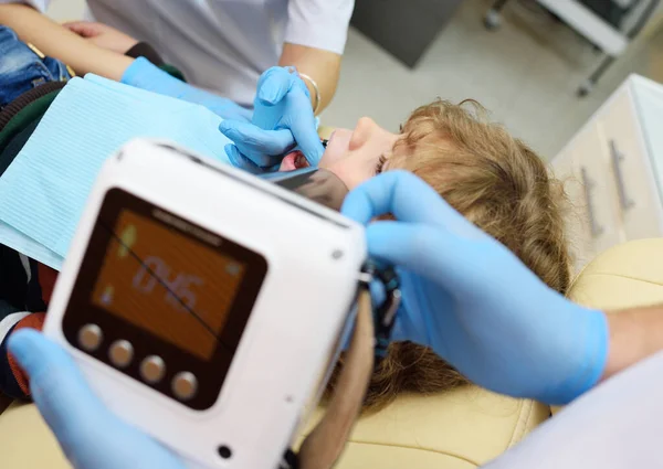 Close-up dentist in rubber gloves does an X-ray of the teeth of a child patient in a modern dental clinic. — Stock Photo, Image