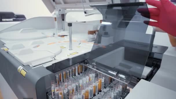 Dipendente donna di un moderno laboratorio microbiologico invia campioni di sangue a un analizzatore di sangue laboratorio biochimico. — Video Stock