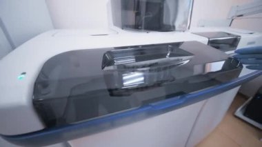 Biyokimya laboratuarındaki bir araştırmacının lastik eldiveni içindeki bir elin yakın plan fotoğrafı modern bir analiz cihazına içinde kan olan test tüpleri olan bir kap yerleştirir.