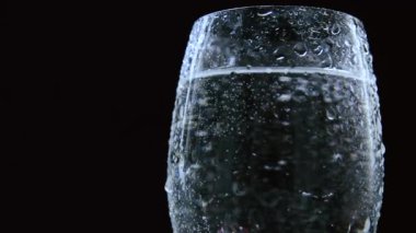 Cam ya da vazo ile su ya da şeffaf bir sıvı ile güzel damlacıklar ile yakın plan koyu bir zemin üzerinde.