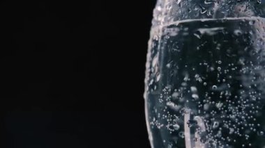 pure natural mineral carbonated water is poured into a beautiful glass. Drops of liquid flow down the glass on a dark background.