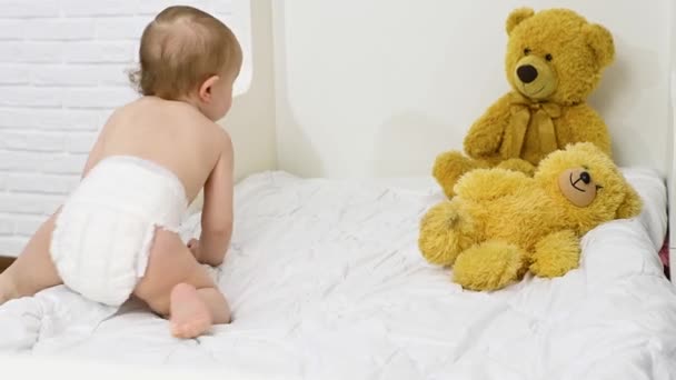 Bebé niño en un pañal desechable se levanta de la cama en la habitación de los niños — Vídeo de stock