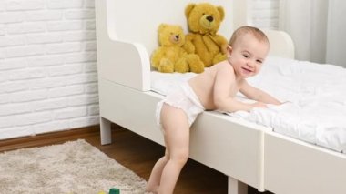 Bebek bezi takmış, gülümseyen çocuk beşiğinden kalkar ve ilk adımı atar.