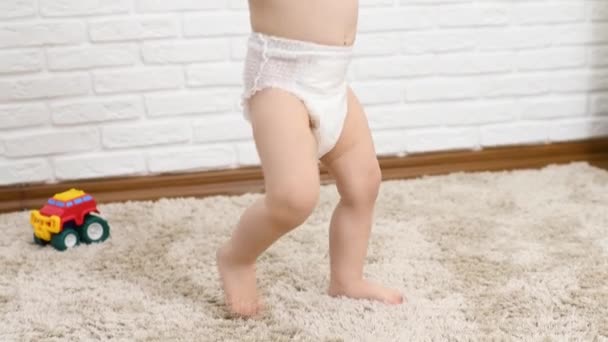 Close-up of a childs feet in a diaper walking on the carpet barefoot — Stockvideo