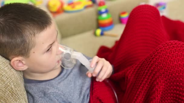 Child teenager boy breathes through an inhaler or nebulizer — Stockvideo