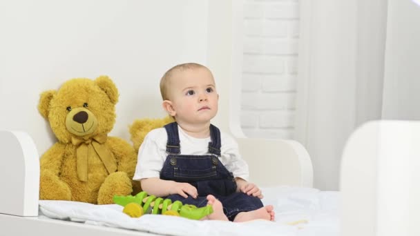 Bebé Mono Mezclilla Mira Televisión Mientras Está Sentado Cama Con — Vídeo de stock