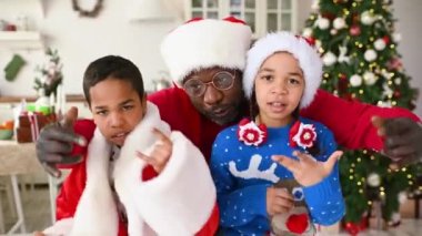 Afrikalı Amerikalı aile - Noel Baba 'nın baba, kız ve oğlu ve sakalı hip hop dansı yapıyor, eğleniyor ve Noel ağacının arka planında sarılıyor..