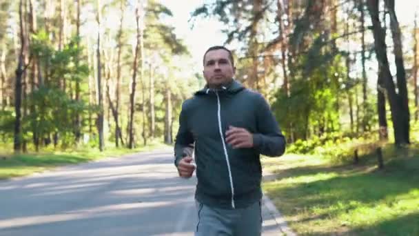 Egy férfi a parkban vagy az erdőben fut az utcán. Lassított mozgás koncepciója. — Stock videók