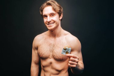 Elinde prezervatifle paketi açan adam.