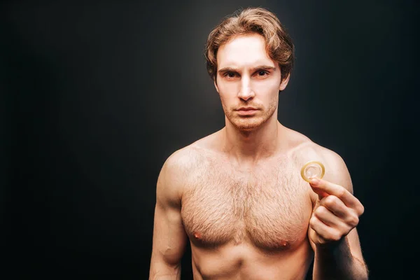Hombre europeo serio mostrando condón en la mano — Foto de Stock