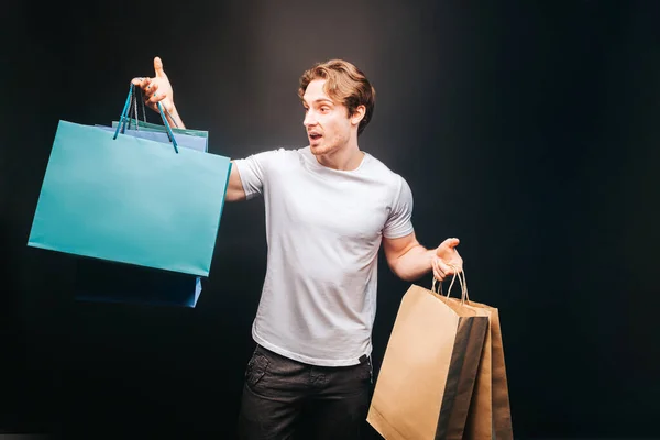 Joven hombre europeo eligiendo regalo en bolsas de compras Imagen De Stock