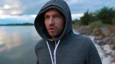 Bir adam nehir ya da denizin kıyısında koşar. Sabah ya da akşam antrenmanı..