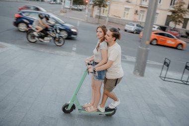 Çiftler güneşli bir günde elektrikli scooter sürerken eğleniyorlar..