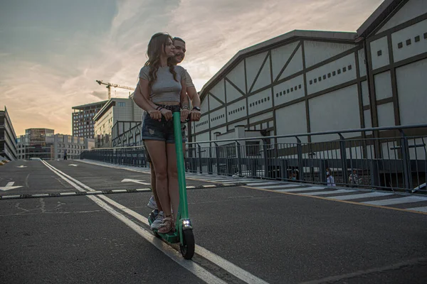Casal está se divertindo dirigindo scooter elétrico ao redor da cidade. — Fotografia de Stock