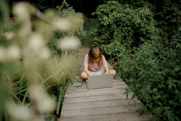 Мила дитина грає на ноутбуці в саду — стокове фото