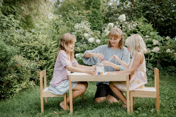 Madre sta dipingendo con i suoi figli in giardino Foto Stock