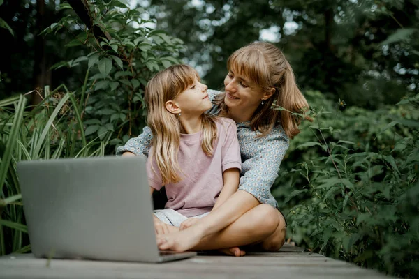 Joven madre y el niño están jugando en el ordenador portátil en el jardín Fotos De Stock