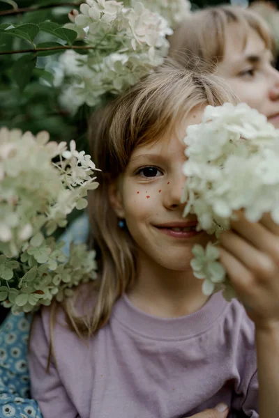 Primer plano de linda chica joven está sonriendo y sosteniendo la flor. Imagen De Stock