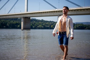 Kumsalda duran yakışıklı ve kaslı adam.