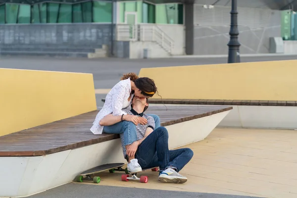Δυο σκέιτερ που φιλιούνται κάθονται μαζί σε μια σανίδα, έξω στον αστικό χώρο. Νεολαία, ρομαντισμός και αγάπη — Φωτογραφία Αρχείου
