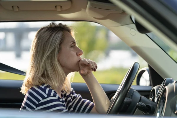 Una mujer muy ansiosa conduciendo un auto. Conductora de mediana edad pensativa triste espera en el atasco de tráfico — Foto de Stock