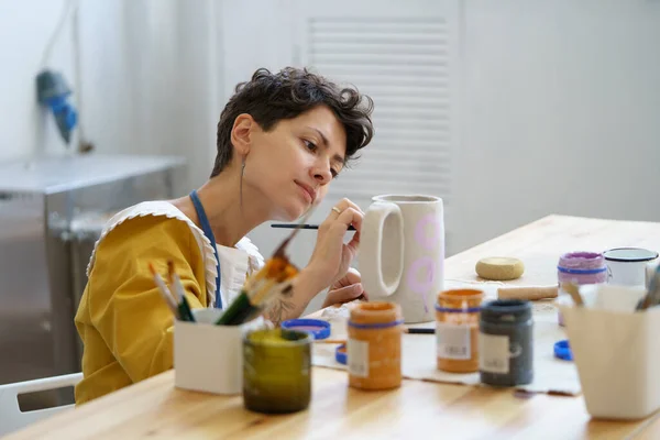 Młoda kobieta spędza czas w studiu ceramicznym pracując nad ceramiką zrelaksowana i szczęśliwa ciesząc się lekcjami sztuki — Zdjęcie stockowe
