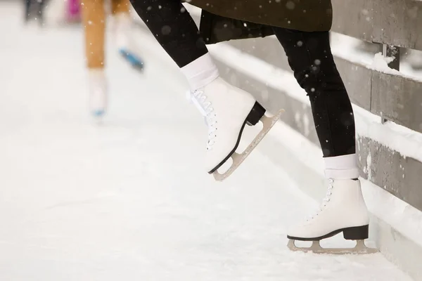 オープンスケートリンク サイドビューで女性スケーターの足のクローズアップ 氷の上の女性の白いスケート 壁の近くの列車 バランスを学ぶ 寒い日の週末の活動屋外 — ストック写真