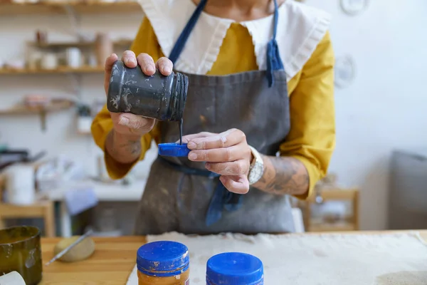 Schilderen aardewerk: vrouwelijke keramist bereiden verf voor het versieren van keramiek in pottenbakker atelier — Stockfoto