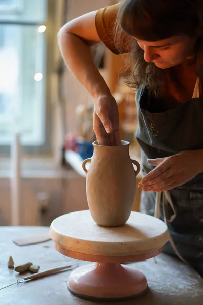Сосредоточенная художница, которая делает вазу для горшечника в студии. Владелец магазина ремесел, создающий новый кувшин для керамики — стоковое фото